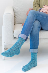 Woman sitting in chair modelling handknit socks with lace